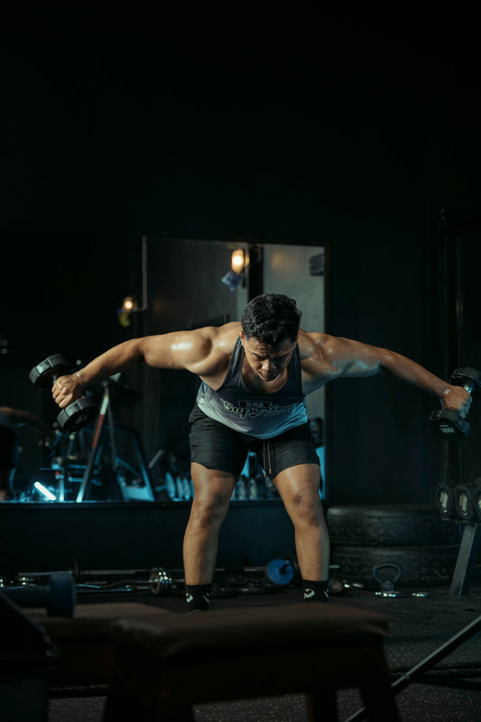 Athlete training with dumbbells in a dark gym
