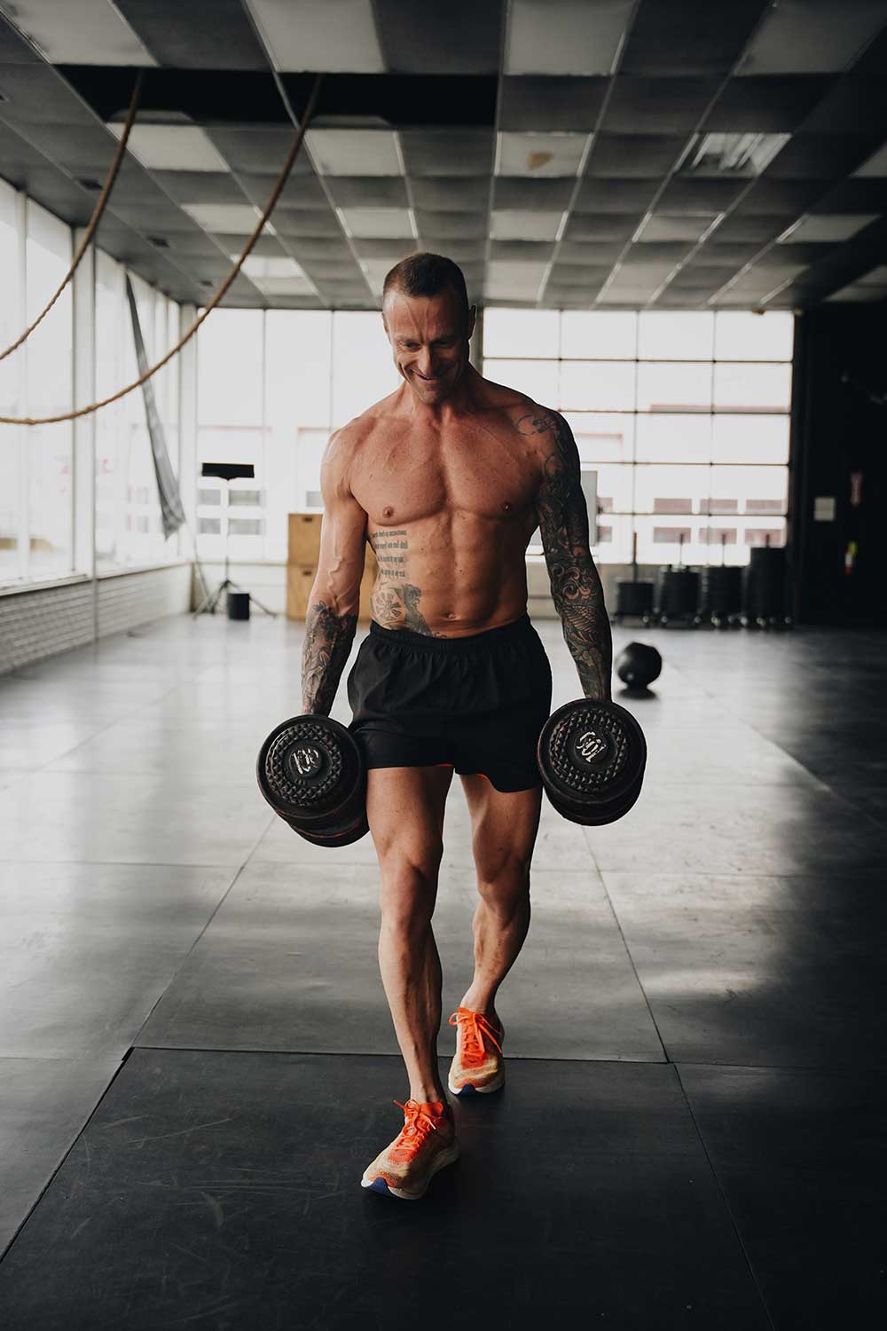Athlete performing a heavy farmer's carry with dumbbells in a gym