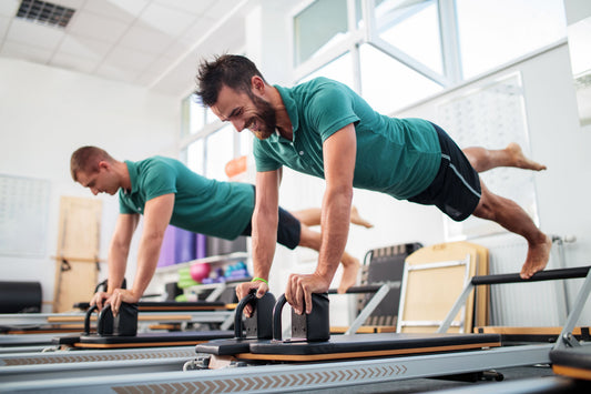 Men training on Pilates reformers