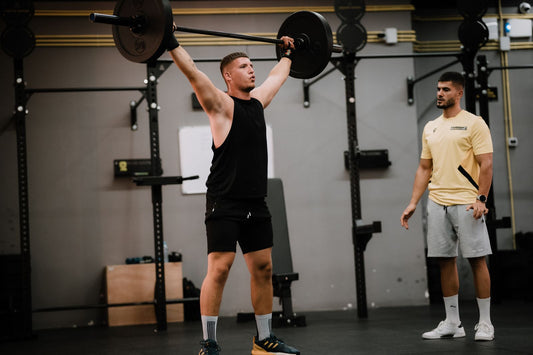 Lifter training with a coach in a gym, representing smarter training habits