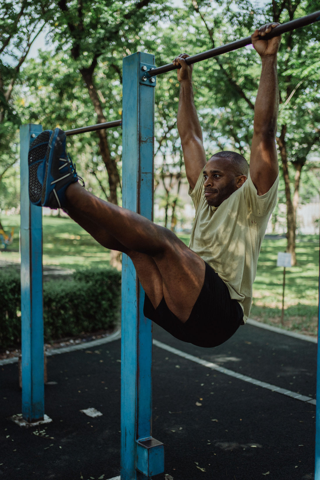 Athlete performing a strict hanging leg raise on an outdoor pull-up bar