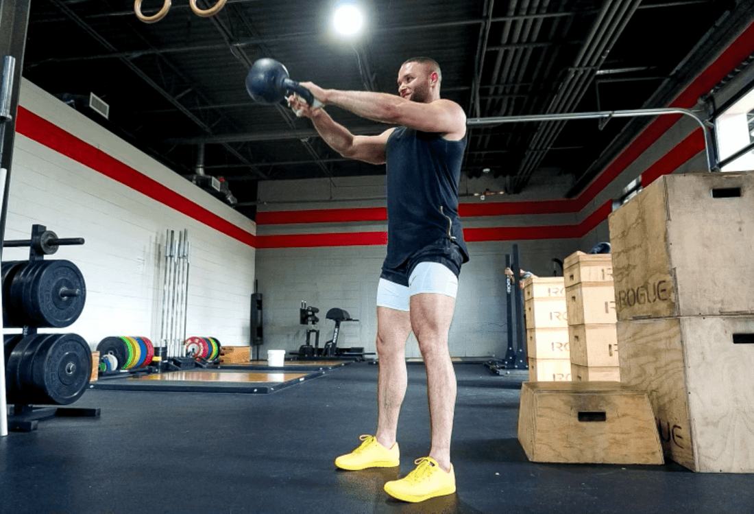 Athlete performing a kettlebell swing in a functional fitness gym