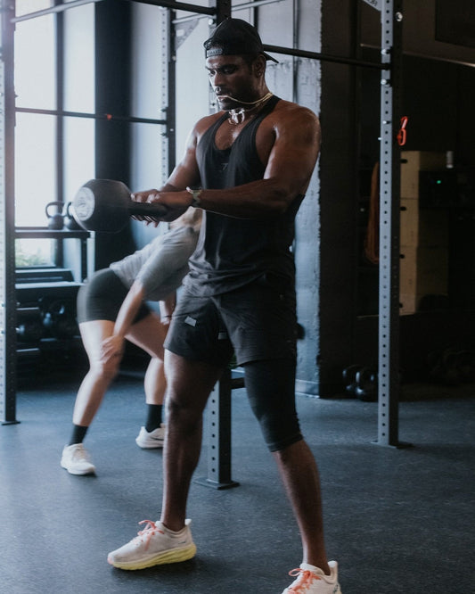 Muscular athlete in a black tank top training with a kettlebell