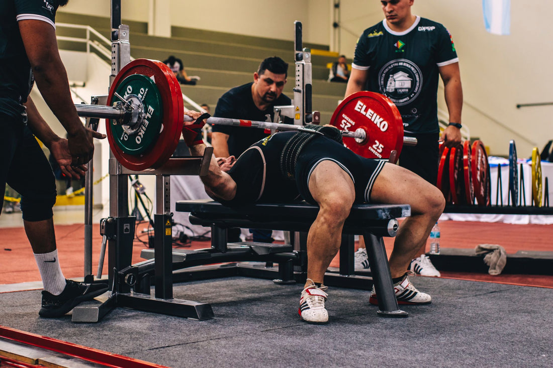 Heavy raw bench press competition with spotters and loaded barbell