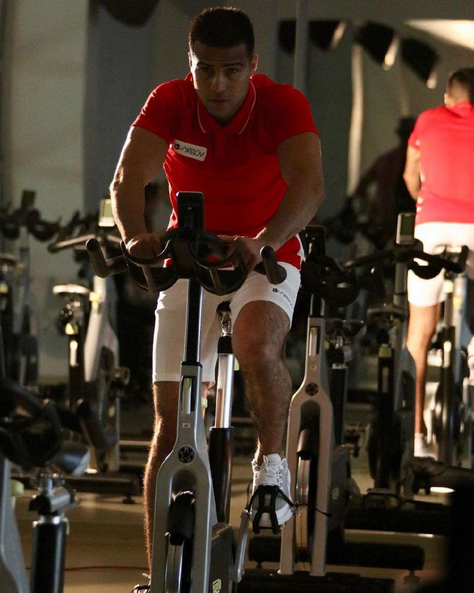 Athlete cycling hard on a stationary bike in a gym