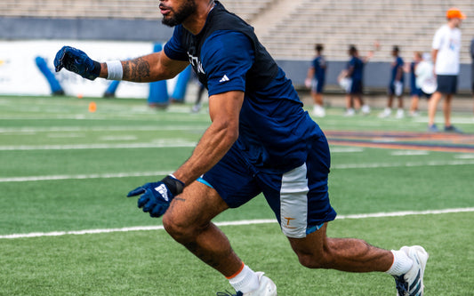 Football athlete accelerating through a cone drill on an outdoor field