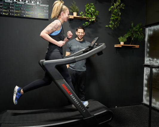 Athlete running hard on a curved treadmill during coached interval training