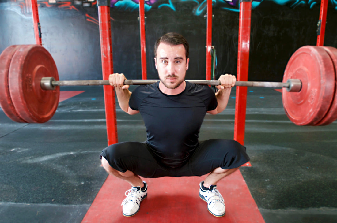 Bodybuilder in a deep squat illustrating range of motion for muscle growth