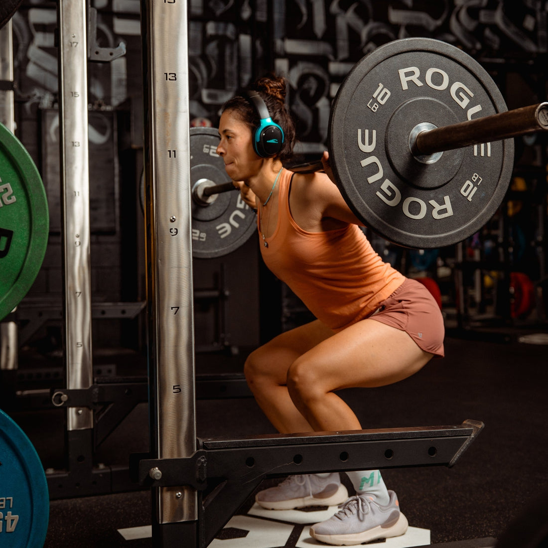 Athlete squatting with headphones during a rock workout playlist