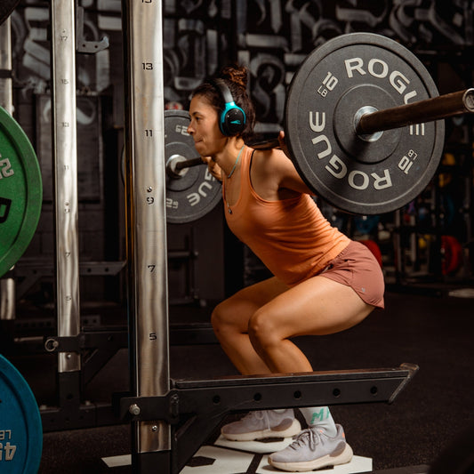 Athlete squatting with headphones during a rock workout playlist