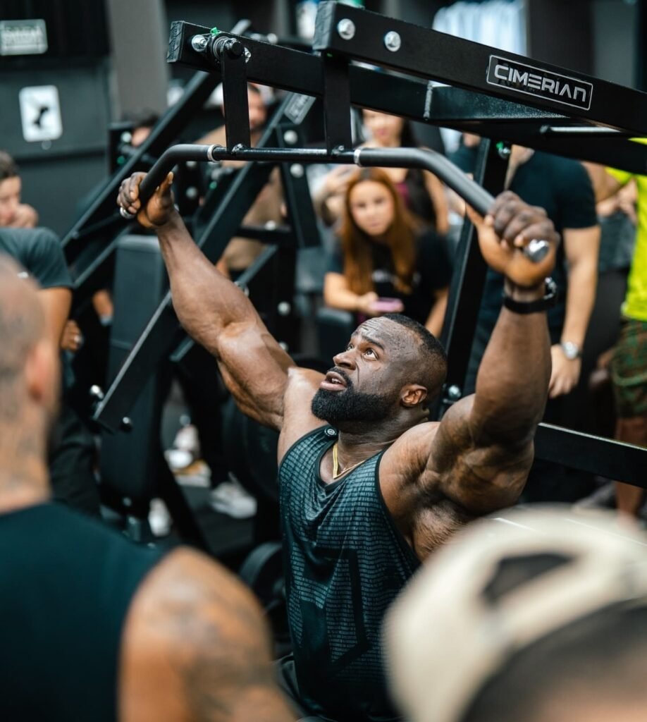 Samson Dauda training on a lat pulldown machine during bodybuilding preparation
