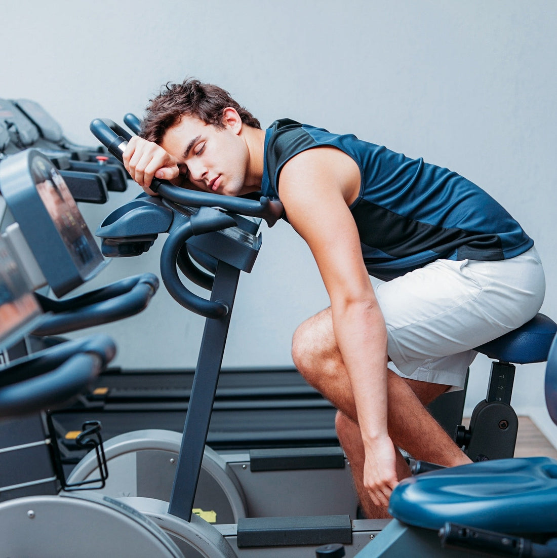 Exhausted man resting on a stationary bike after too little sleep
