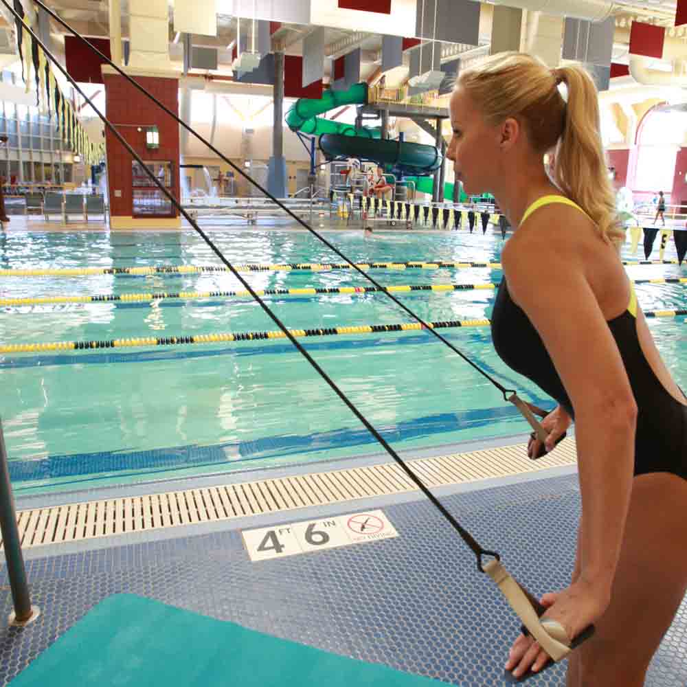 Competitive swimmer performing dryland strength training beside a pool