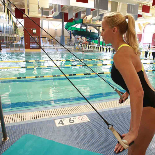 Competitive swimmer performing dryland strength training beside a pool