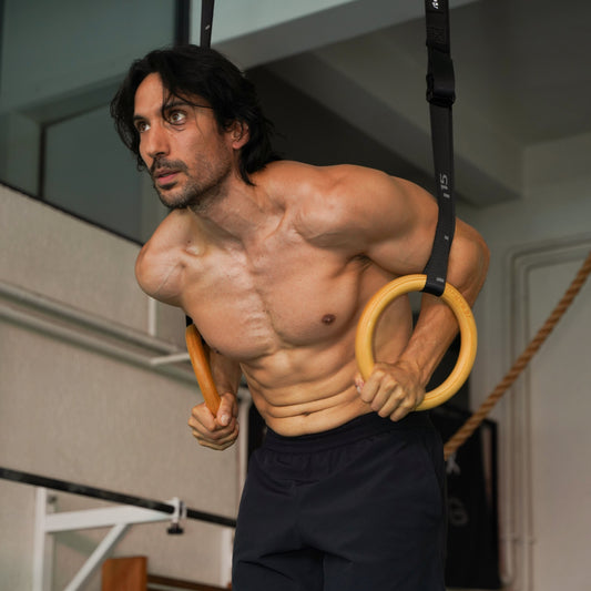 Athlete performing a controlled ring dip on wooden gymnastics rings