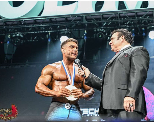 Ryan Terry posing on the Men’s Physique Olympia stage with a wide V-taper, developed shoulders and a tight midsection