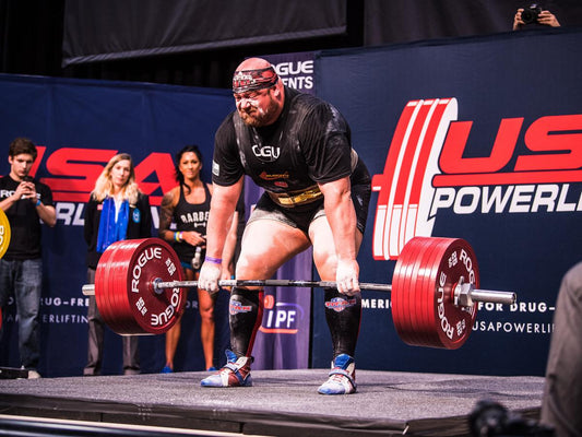 Competitive powerlifter lifting on a platform as bodyweight strength standards are compared