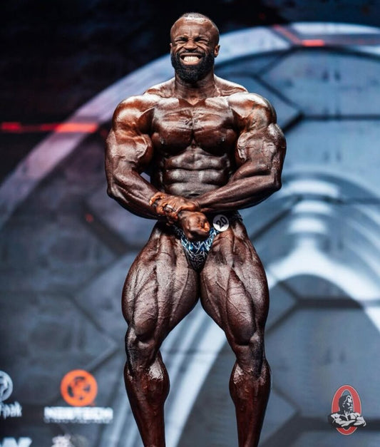 Samson Dauda posing on a bodybuilding stage