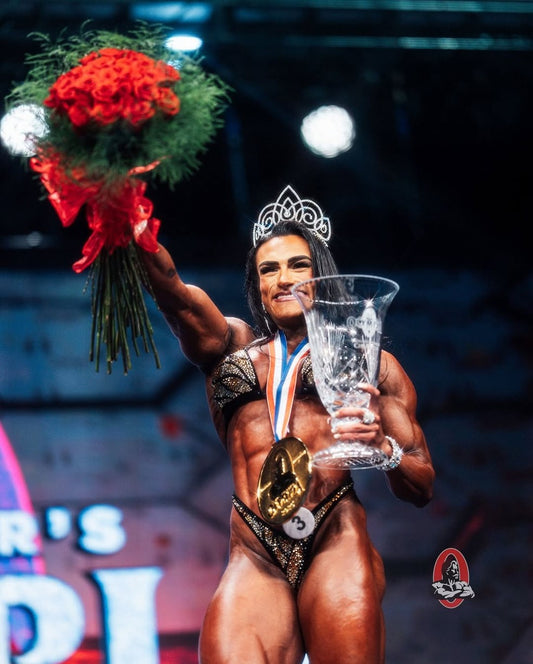 Natalia Coelho posing on the Women’s Physique Olympia stage