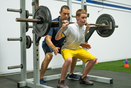 Teen athlete performing a supervised barbell squat