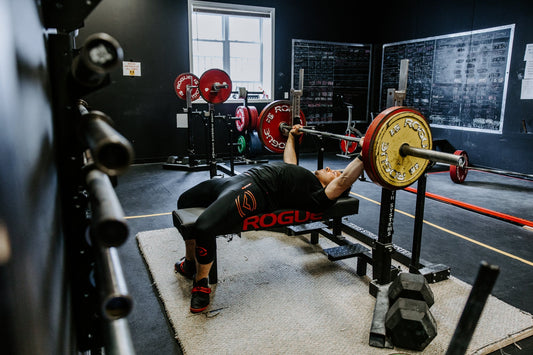 Powerlifter bench pressing a loaded barbell in a strength gym