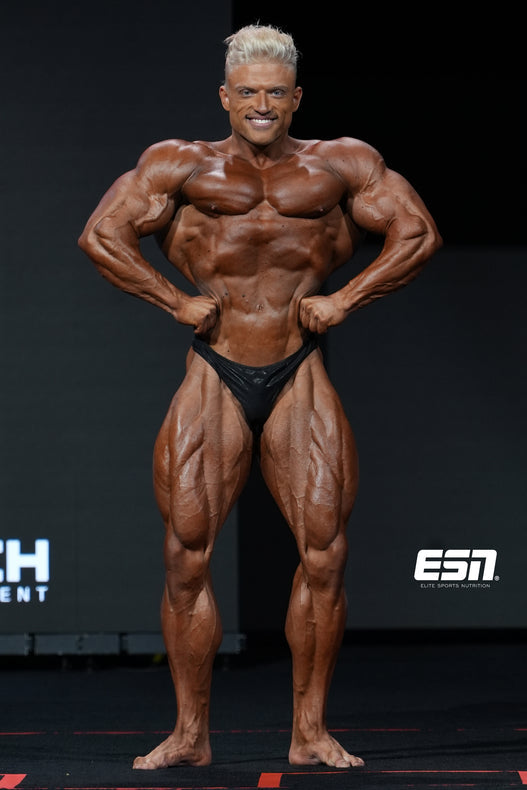 Urs Kalecinski showing his muscular front lat spread at the 2024 Olympia