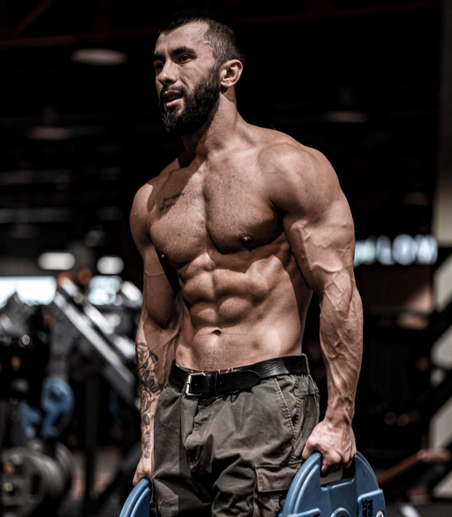Vladimir Shmondenko, known as Anatoly, showing his muscular physique while holding weight plates in a gym
