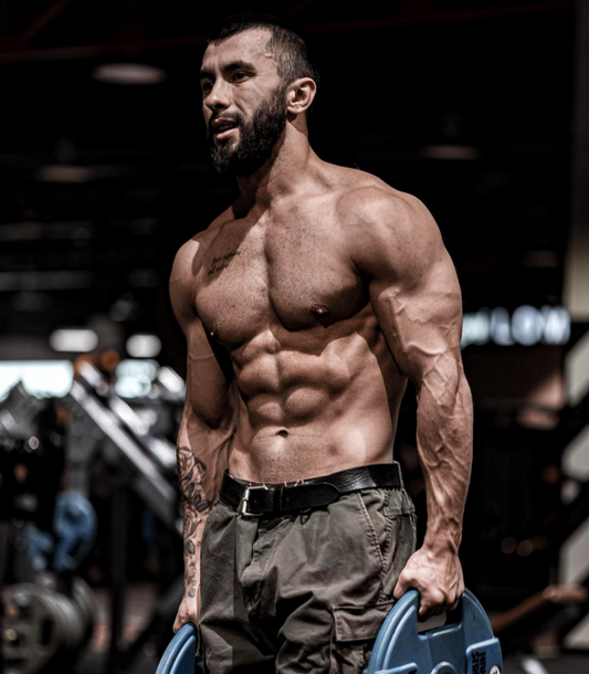 Vladimir Shmondenko, known as Anatoly, showing his muscular physique while holding weight plates in a gym