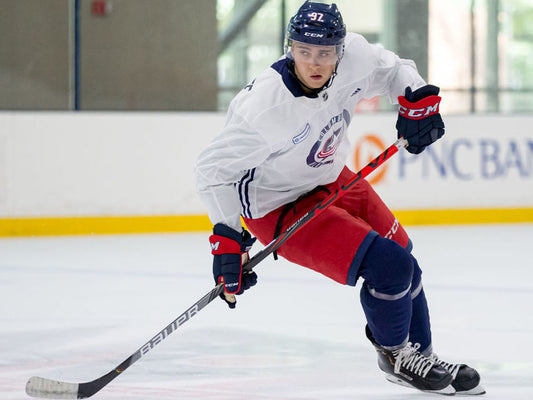 Hockey player skating around a cone on an indoor ice rink
