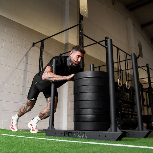 Athlete performing a loaded sled exercise on indoor gym turf