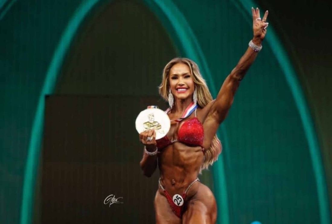 Francielle Mattos holding a Wellness Olympia medal and celebrating onstage.