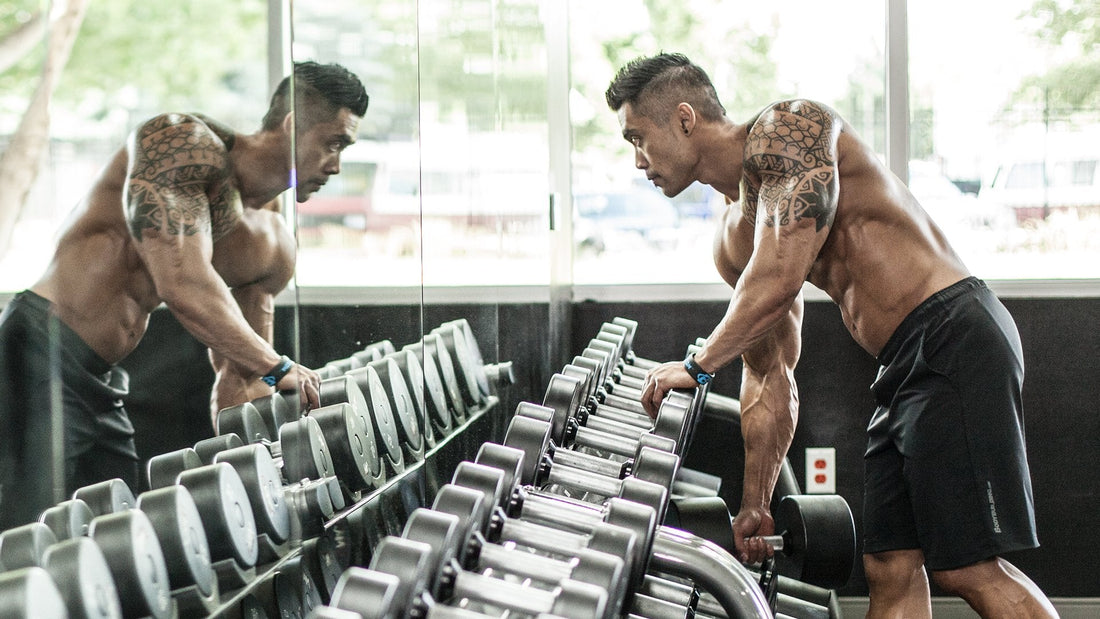 Strength athlete choosing dumbbells from a rack in a commercial gym