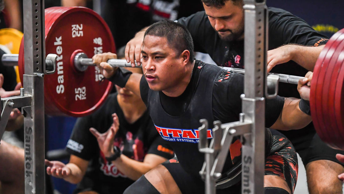 Powerlifter squatting with a loaded barbell on a competition platform