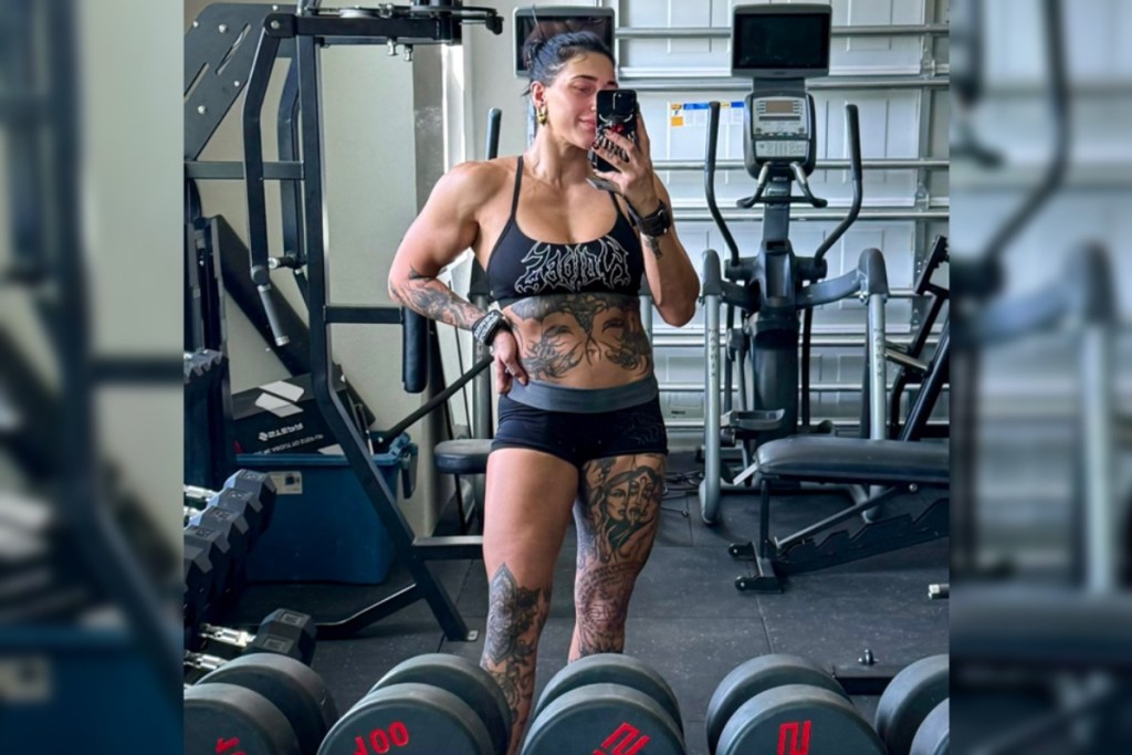 Rhea Ripley flexing her muscular arms in a gym