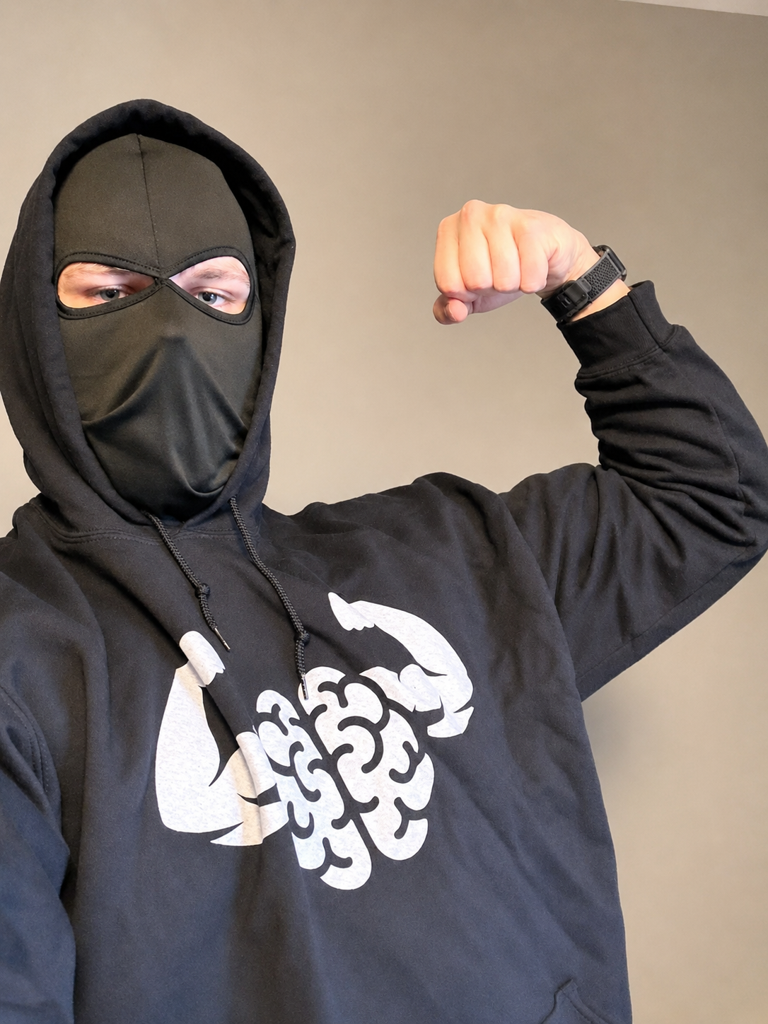 Mind Muscle Perfection home gym influencer flexing in a black hoodie with the new MMP logo designed by Next Cult Brand, featured in the Mind Muscle Perfection merch collection for smart lifters, home gym fans, and science-based workout apparel shoppers.