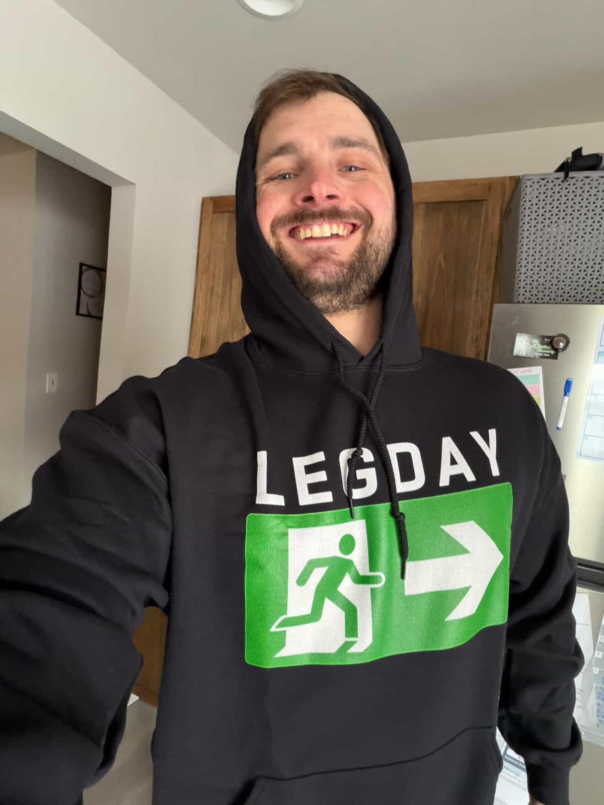 Luke from Luke’s Garage Gym smiling in a black Leg Day hoodie from Next Cult Brand, featured in the Luke’s Garage Gym merch collection for home gym lifters, garage gym fans, and funny workout apparel shoppers.